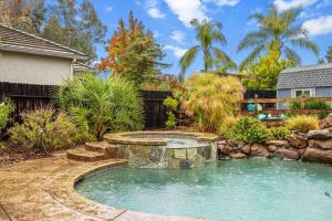 a pool with a waterfall in a backyard with a landscaping at Tranquil Retreat: Pool, Spa, Firepit, Peloton, WFH in Orangevale