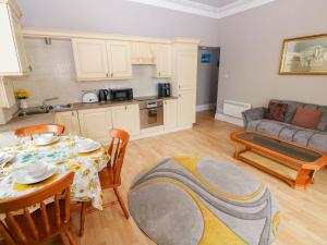 a kitchen and a living room with a table and chairs at 1 Hilton Flats in Tenby