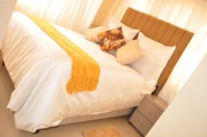 a white bed with pillows and a yellow blanket on it at RosiMug's Homestay in Umtali