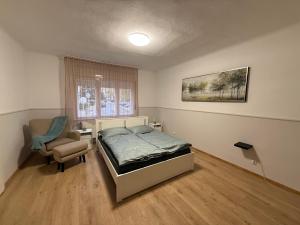 a bedroom with a bed and a chair and a window at 7Csakra Vendeghaz in Szentendre