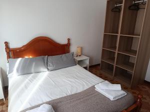 a bedroom with a bed with white sheets and shelves at A Ribeira in Fene