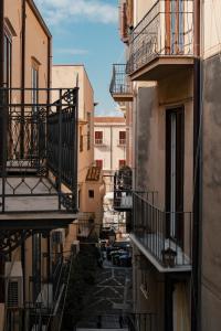 an alley between two buildings with balconies and cars at Dimora Costa Cefalù in Cefalù