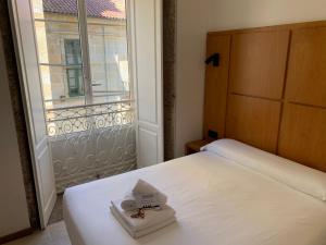 a bedroom with a white bed and a window at Libredón Rooms in Santiago de Compostela