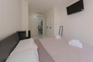 a white bedroom with a bed and a flat screen tv at Dimora Costa Cefalù in Cefalù +16 photos