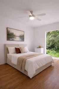 a white bedroom with a bed and a ceiling fan at M&M Pousada in Petrópolis