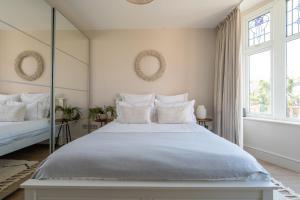 a white bedroom with a large bed and windows at Blu's Seaview Apartment in Rhos-on-Sea