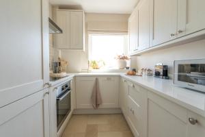 a white kitchen with white cabinets and a window at Blu's Seaview Apartment in Rhos-on-Sea