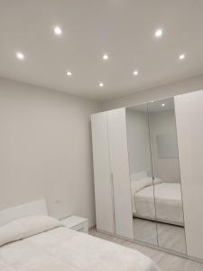 a white bedroom with a mirror and a bed at Grazia Nest in Ciampino
