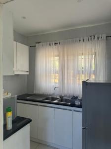 a kitchen with white cabinets and a sink and a window at RosiMug's Homestay in Umtali