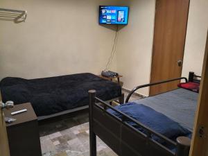 a room with two beds and a tv on the wall at El Cubanito Cafe y hospedaje in León