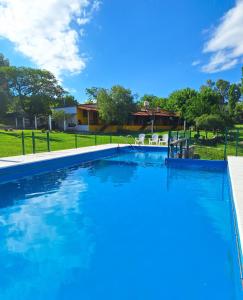 a large pool with blue water in a yard at Cabañas El Refugio de Juan in Mina Clavero