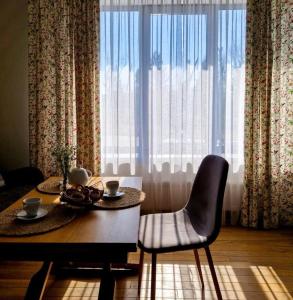 a dining room with a table and chairs and a large window at Mayachok Boutique hotel in Kyiv