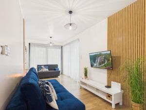 a living room with a blue couch and a tv at Baltic Horizon Klifowa by Solarento in Rewal