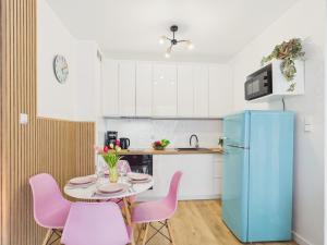 a kitchen with a table with pink chairs and a blue refrigerator at Baltic Horizon Klifowa by Solarento in Rewal