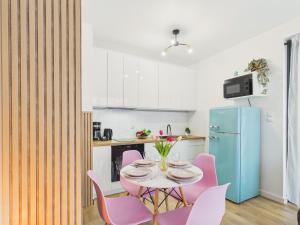 a kitchen with a table with pink chairs and a blue refrigerator at Baltic Horizon Klifowa by Solarento in Rewal