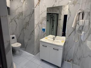 a bathroom with a sink and a toilet and a mirror at Three Dolphins Hotel in Aktau +28 photos