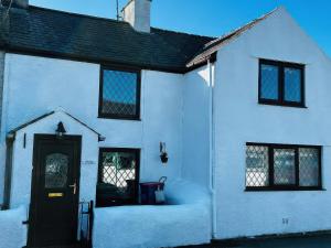 a white house with a black door in the snow at Preswylfa in Cemaes Bay