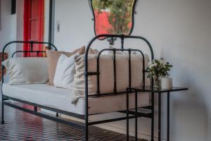 a black iron bed with white pillows and a table at Casa Cielo Cardenal in Concepción del Uruguay