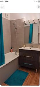 a bathroom with a tub and a sink and a mirror at Appartement T2 cosy in Canteleu