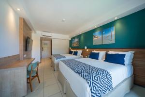 a hotel room with two beds and a desk at Salinas Maceio All Inclusive Resort in Maceió