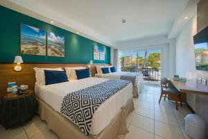 a hotel room with two beds and a desk at Salinas Maceio All Inclusive Resort in Maceió
