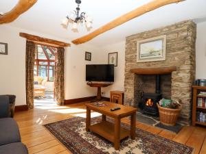 a living room with a fireplace and a tv at Oak Tree in Halwell