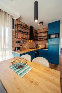 a kitchen with blue cabinets and a wooden table at Zara Garden Apartment in Novi Sad