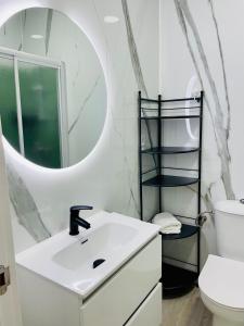 a white bathroom with a sink and a mirror at Puerto playa B in Malpica +12 photos