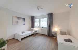 a living room with two beds and a window at BEGE APARTMENTS SmileStay in Gelsenkirchen +11 photos