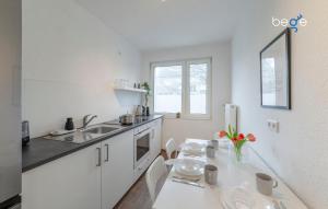 a white kitchen with a table and a sink at BEGE APARTMENTS SmileStay in Gelsenkirchen