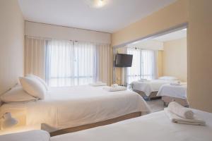 a hotel room with two beds and a mirror at Rayentray Hostal in Puerto Madryn