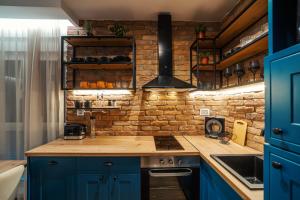a kitchen with blue cabinets and a brick wall at Zara Garden Apartment in Novi Sad