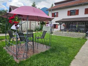 Ein Tisch und Stühle unter einem rosa Sonnenschirm in einem Garten in der Unterkunft Forest Vila in Buşteni