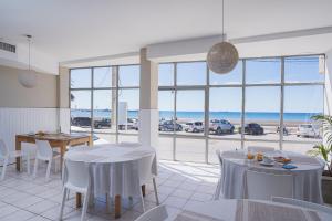a dining room with tables and chairs and a view of the ocean at Rayentray Hostal in Puerto Madryn