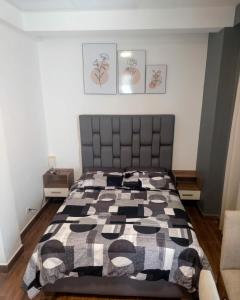 a bedroom with a bed with a black and white quilt at Tu Refugio Acogedor a Pasos de Todo in Cochabamba