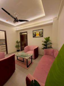 a living room with pink chairs and a glass table at Go Glam Hotels Bahria Town in Rawalpindi