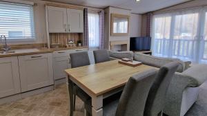 a kitchen and living room with a table and chairs at Rocco Family Retreat, Green Lawns in Selsey