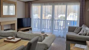 a living room with couches and a television and a balcony at Rocco Family Retreat, Green Lawns in Selsey