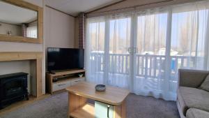 a living room with a couch and a television and a fireplace at Rocco Family Retreat, Green Lawns in Selsey +5 photos