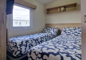 two beds in a small room with a window at Serena Little Escape, West Sands Holiday in Selsey +2 photos