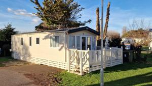a small white shed with a white fence at Memories Made, Quiet Holiday, Green Lawns in Selsey