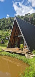 a small house with a black roof and a wooden deck at Chalé Suíço com Jacuzzi in Marechal Floriano