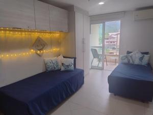 a bedroom with two beds with lights on the wall at Inefável flat Porto Marina Resort in Mangaratiba +23 photos