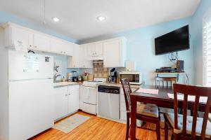 a kitchen with white appliances and a table with chairs at Oceanbound in Folly Beach