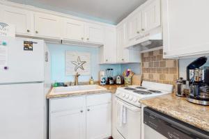 a kitchen with white cabinets and a white refrigerator at Oceanbound in Folly Beach