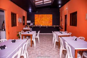 a restaurant with white tables and white chairs and a screen at Hotel Estação Trem Guararema in Guararema