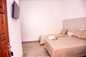 a small room with two beds and a tv at Hotel Estação Trem Guararema in Guararema
