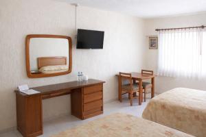 a hotel room with a desk and a mirror at Hotel Acámbaro Plaza in Acámbaro