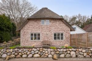 a brick house with a stone retaining wall in front of it at Küsten Kate in Ording