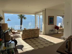 a living room with a couch and a large window at Casa Rocca Nera by HolAp in Ronco sopra Ascona +23 photos